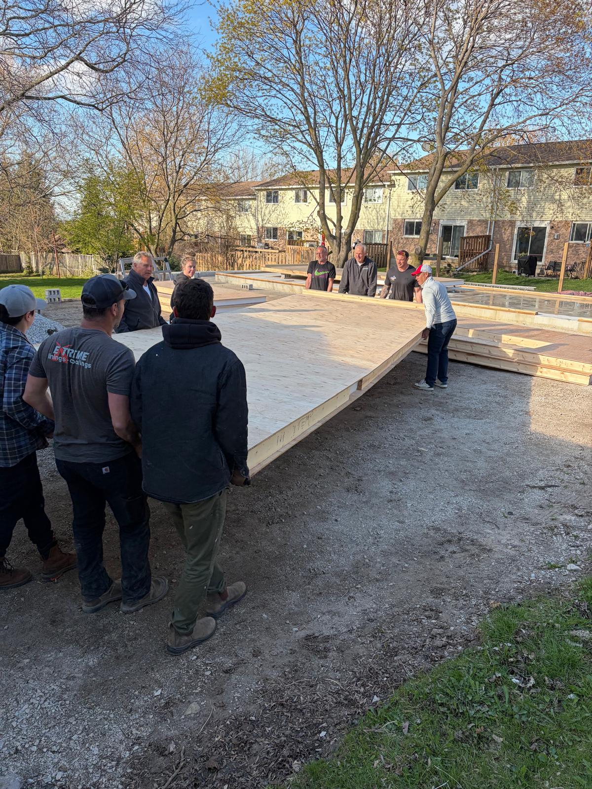 Foam House construction crew gathered around completed foundation slab ready to begin SIP panel assembly