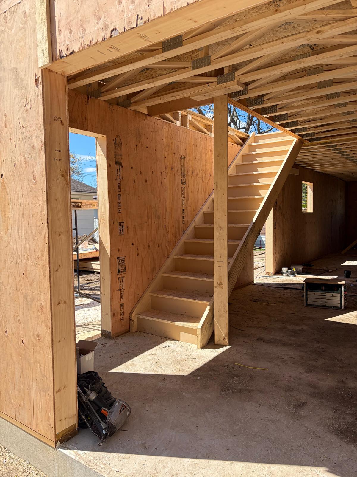 Interior staircase of SIP panel two-story home showing clean construction and roof trusses above