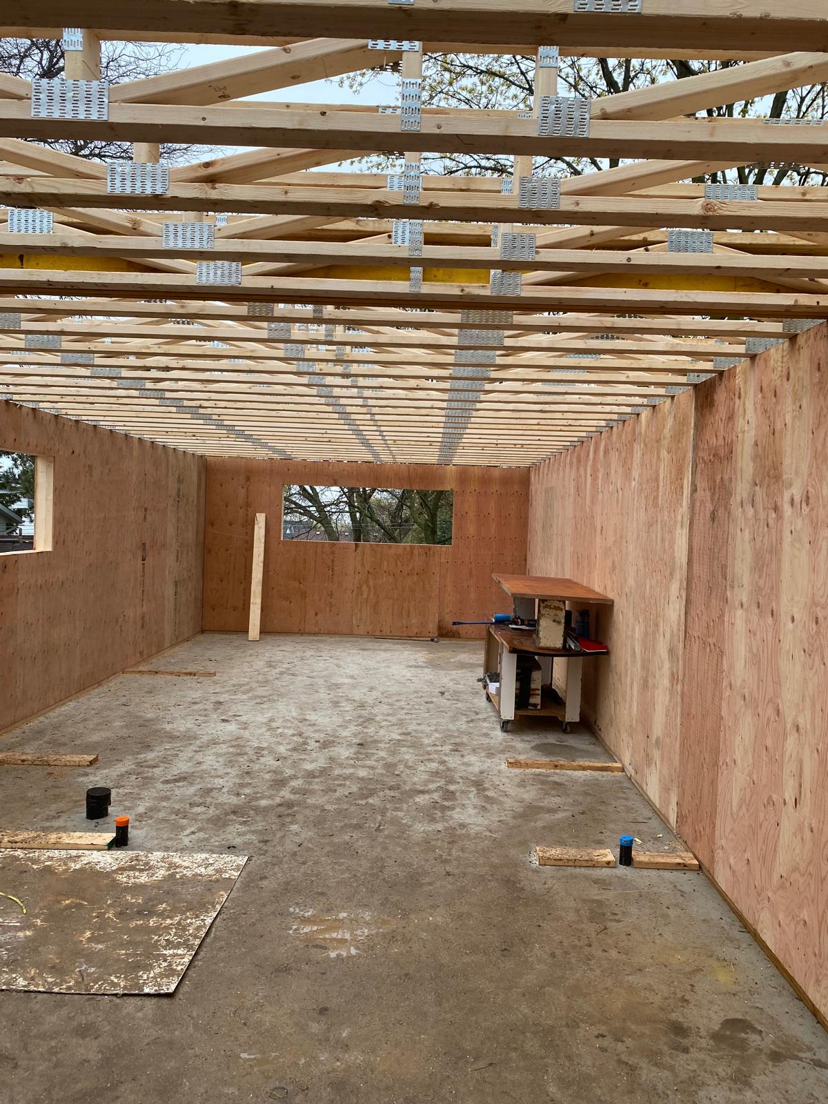 Interior of SIP panel home showing completed roof truss system and window openings with natural light
