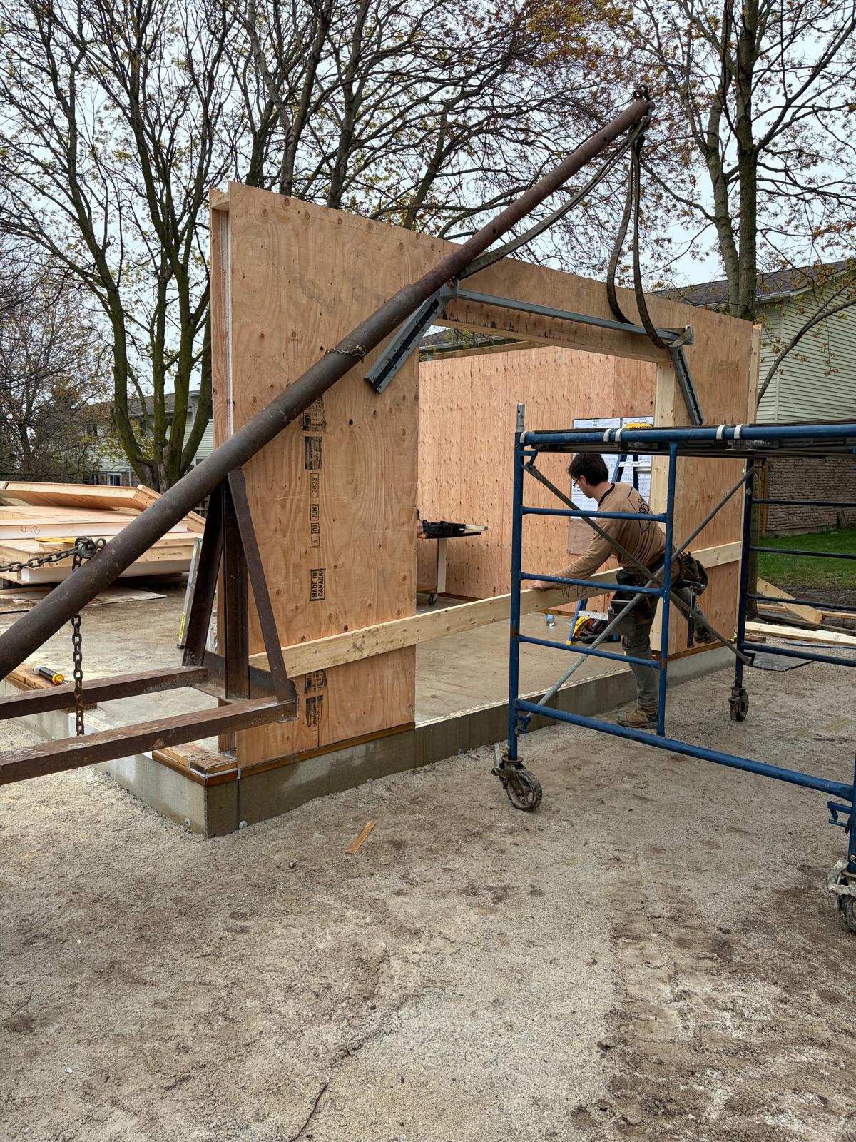 SIP wall panel being tilted up into position using scaffolding during home construction